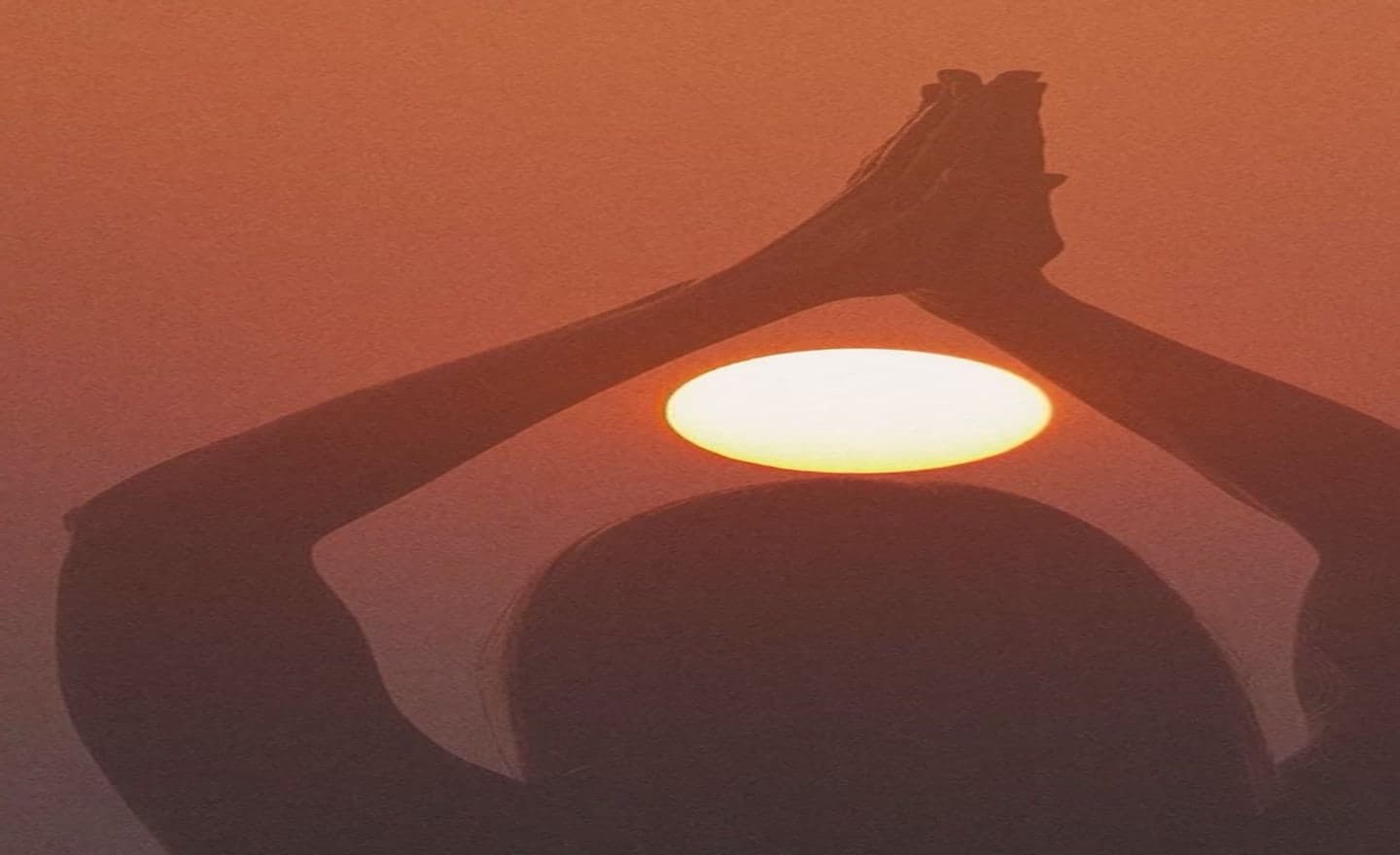 Hands joined above the rising sun